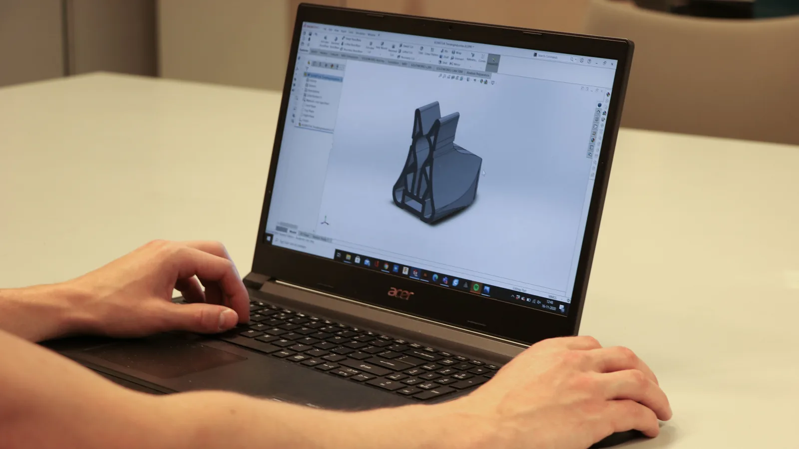 Close-up van handen op een laptop met een CAD-model in beeld